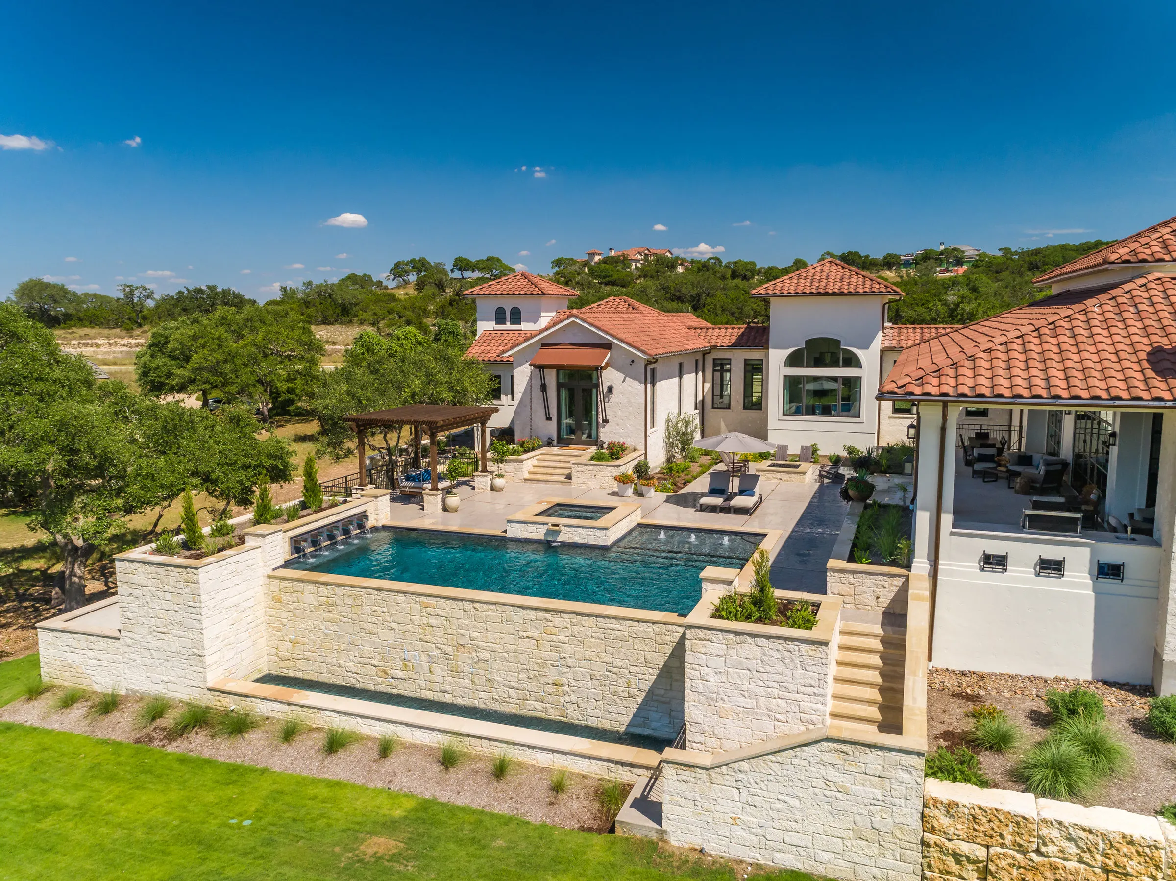 Aerial view of a vanishing edge pool set into a hillside with stone retaining walls and stairs